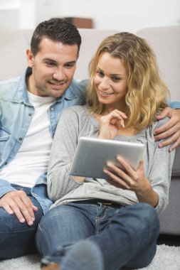 Mutlu genç çift tabletlerinde internet izliyor.