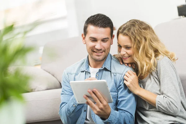 Relaxado jovem casal usando um tablet em sua sala de estar — Fotografia de Stock