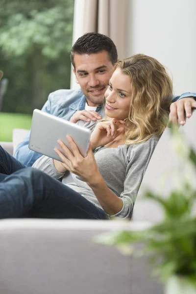 Happy young couple watching internet on their tablet — Stock Photo, Image