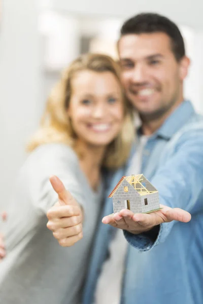 Glada unga par med en modell av deras framtida hus — Stockfoto