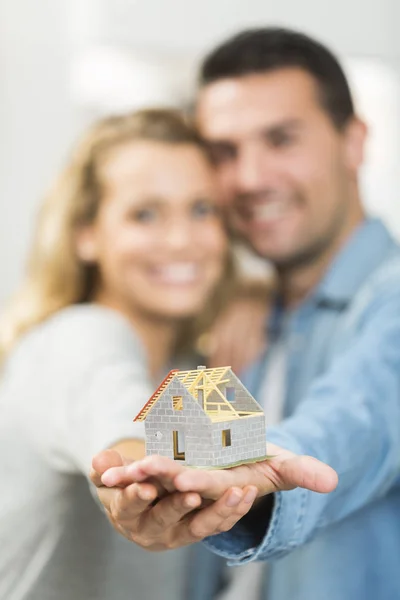 Jovem casal feliz com o modelo de sua futura casa — Fotografia de Stock