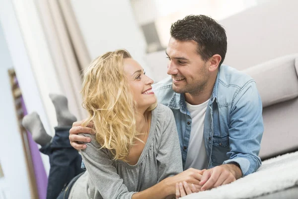 Feliz joven pareja acostada en la alfombra de su sala de estar — Foto de Stock