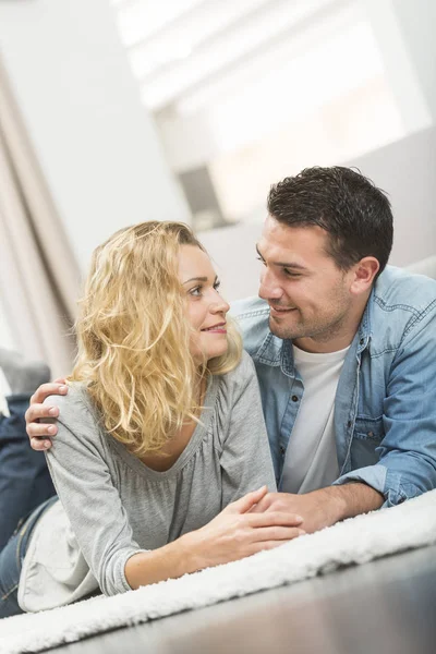 Happy young couple layed on the carpet of their living room — Stock Photo, Image