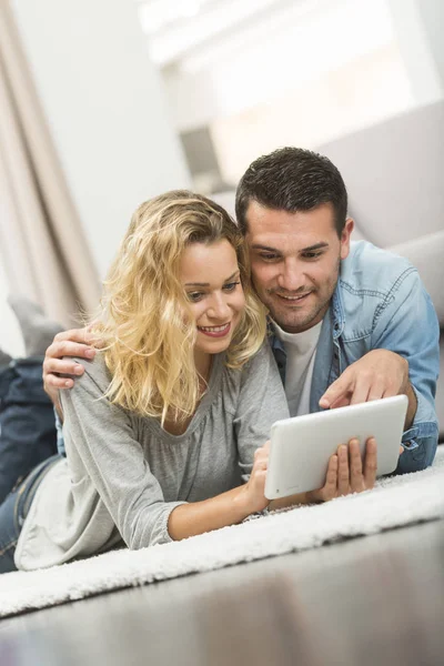 Happy young couple layed on the carpet of their living room and — Stock Photo, Image