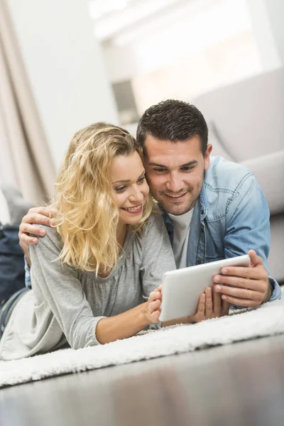 Happy young couple layed on the carpet of their living room and — Stock Photo, Image