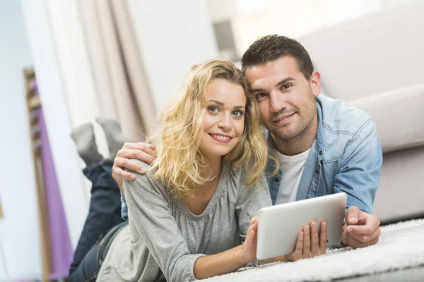 Happy young couple layed on the carpet of their living room and — Stock Photo, Image