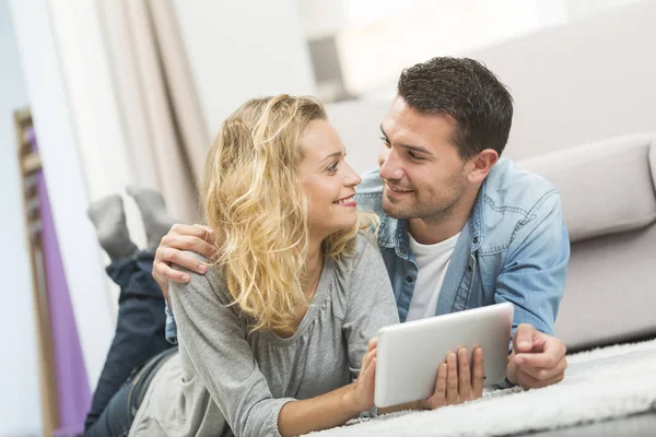 Happy young couple layed on the carpet of their living room and — Stock Photo, Image