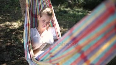 neşeli genç kadın bir hamakta tablet kullanma