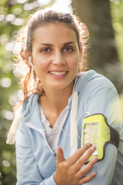 Vrouw met behulp van smartphone na het uitvoeren van op bos in de herfst Stockafbeelding