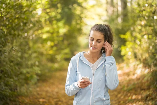 Mujer usando smartphone después de correr en el bosque en otoño Fotos de stock libres de derechos