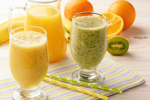 Smoothies orange et kiwi sains à la banane sur fond de bois blanc . — Photo