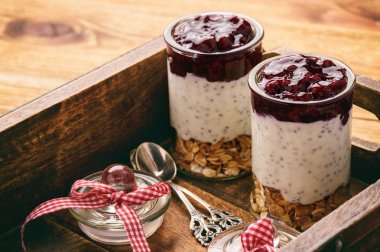 Sağlıklı yoğurt tatlı wih chia tohum, müsli ve ahşap tepsi üzerinde ezilmiş meyveler.