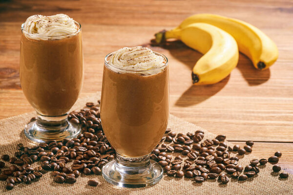 Coffee milk cocktails with banana on wooden background.