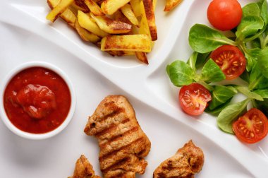 Izgara domuz eti bonfile, salata ve patates kızartması beyaz plaka üzerinde.