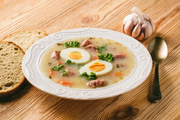 Borscht branco polonês tradicional - zurek, sopa azeda com salsichas brancas e ovos . — Fotografia de Stock