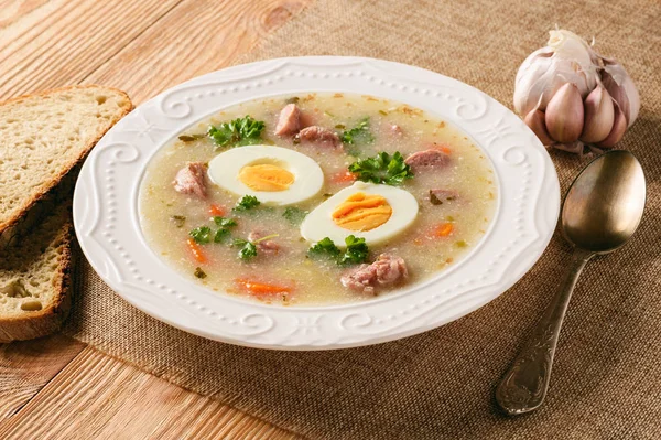Borscht blanco esmalte tradicional - zurek, sopa agria con salchichas blancas y huevos . —  Fotos de Stock