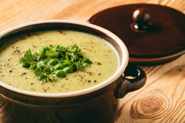 Cream sup dengan kentang, daun bawang dan kacang polong di atas meja kayu . — Stok Foto