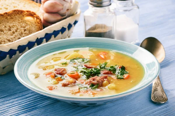 Sopa de guisante con salchicha ahumada sobre fondo de madera azul . — Foto de Stock