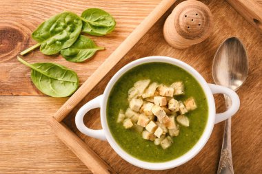 Ahşap tepsi croutons yeşil kremalı sebze çorbası.