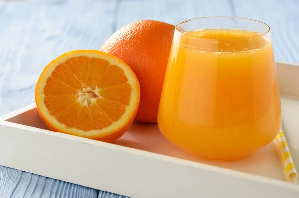 Jus d'orange frais sur fond de bois bleu . — Photo