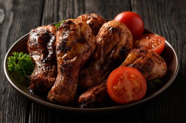 Ahşap arka plan üzerinde domates ile kavrulmuş tavuk budu.