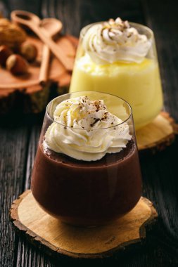 Kremalı ve çikolatalı puding ahşap zemin üzerine krem şanti ile.