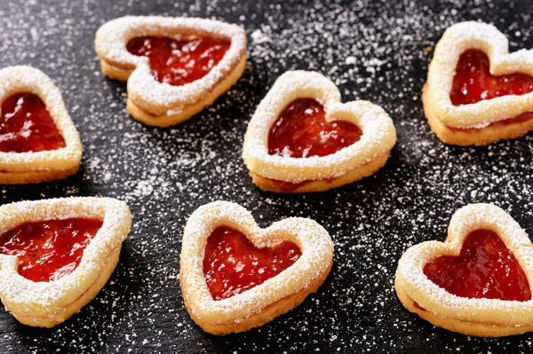 Homemade shortbread heart cookies on black background.