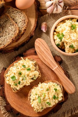 Kepekli sandviç yumurta ve peynir ile ahşap güdük yaymak.