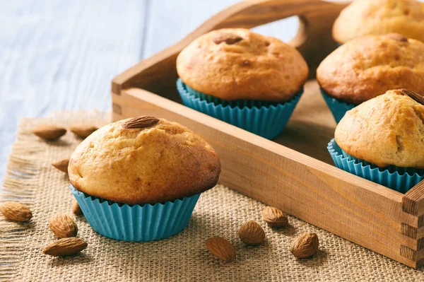 Süße Muffins mit Mandeln auf blauem Holztisch. — Stockfoto