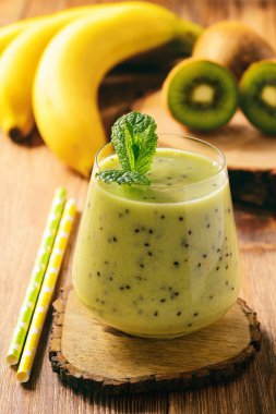 Koyu ahşap zemin üzerine muz ve kivi güler yüzlü.