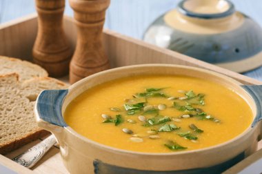 Ahşap masa üzerinde sarı sebze krem çorbası.