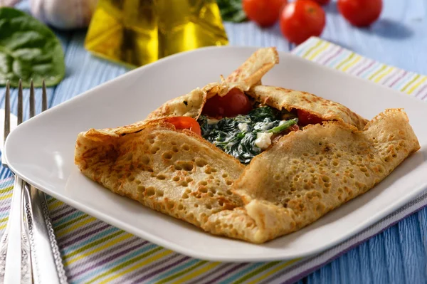 Pancake stuffed with spinach, feta cheese and tomatoes. — Stock Photo, Image