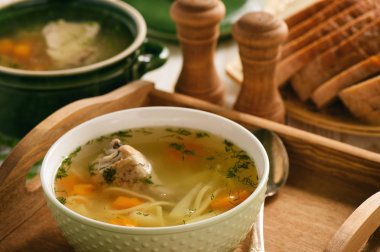 Ahşap tepsi üzerinde bir kapta tavuk çorbası.