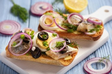 Yumurta, kırmızı soğan ve dereotu ile ringa balığı sandviç.