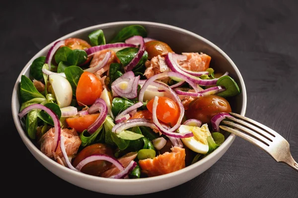 Salad with salmon, tomatoes, eggs and red onion.