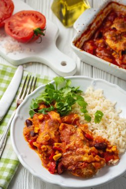 Domates sosunda pişirilmiş tavuk fileto mısır ve fasulye, haşlanmış pirinçle servis edilir. Meksika usulü mutfak..