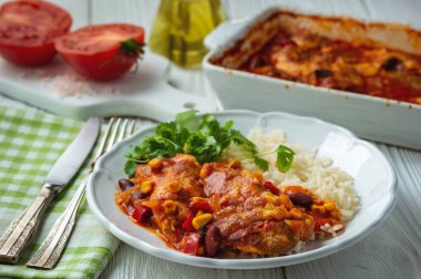 Domates sosunda pişirilmiş tavuk fileto mısır ve fasulye, haşlanmış pirinçle servis edilir. Meksika usulü mutfak..