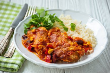 Domates sosunda pişirilmiş tavuk fileto mısır ve fasulye, haşlanmış pirinçle servis edilir. Meksika usulü mutfak..