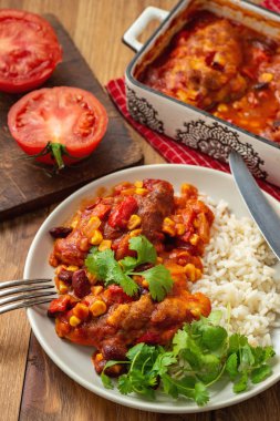 Domates sosunda pişirilmiş tavuk fileto mısır ve fasulye, haşlanmış pirinçle servis edilir. Meksika usulü mutfak..