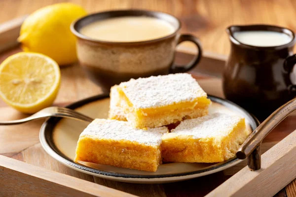 Homemade lemon bars with shortbread crust, on wooden background.