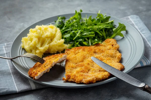 Chop pork cutlets , served with mashed potatoes and arugula.