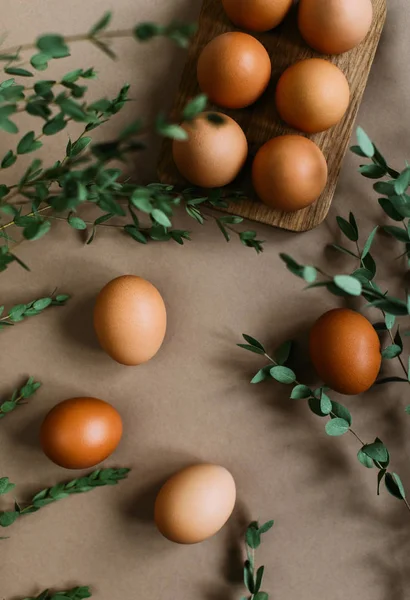 クラフト用紙の背景に緑の枝に囲まれた鶏の卵の山 — ストック写真