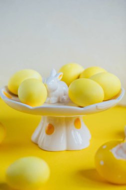 Seramik tavşan ile plaka üzerinde sarı yumurta Paskalya kompozisyon ile boyalı