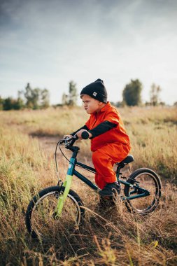 Dışarıda bisiklet süren kasklı küçük çocuk. 