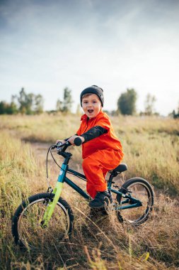 Dışarıda bisiklet süren kasklı küçük çocuk. 