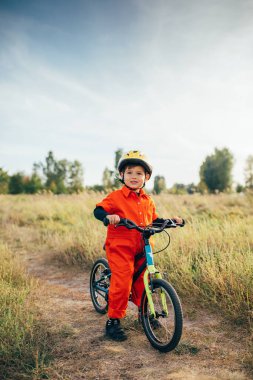 Dışarıda bisiklet süren kasklı küçük çocuk. 