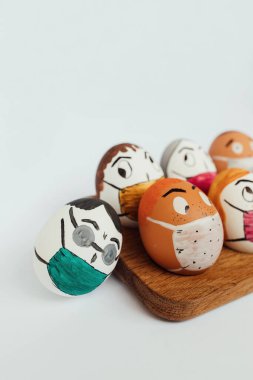 Yumurtalı Paskalya kompozisyonu, üzerine beyaz kağıt arka planda tıbbi maskeli komik yüzler çizilmiş..