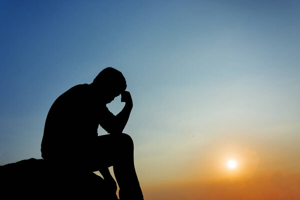 Силуэт человека, сидящего на закате
