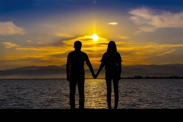男人和女人的剪影 手牵着手 在海边的日落 — 图库照片