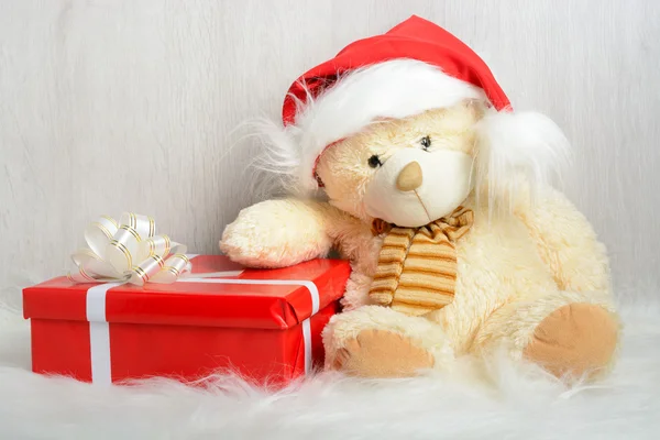 Teddy bear in kerstmuts met geschenken — Stockfoto